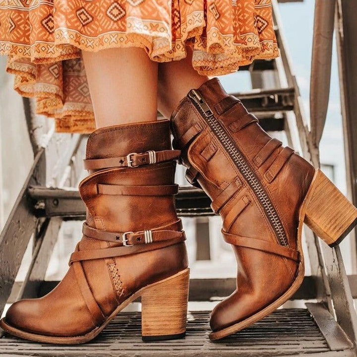 Bruine leren dameslaarzen met hak, gespen en rits, gedragen op een metalen trap. Trendy herfstmode, bohemian stijl, hoogwaardige kwaliteit.