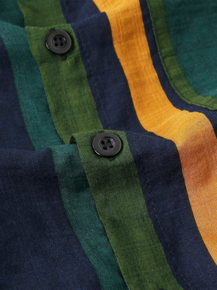 Gestreepte katoenen stof met groene, blauwe en gele banen en zwarte knopen. Ideaal voor modieuze kleding en interieurdecoratie.
