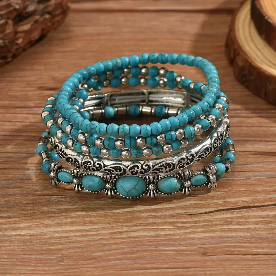 Set van 5 armbanden met turquoise kralen en zilverkleurige details.