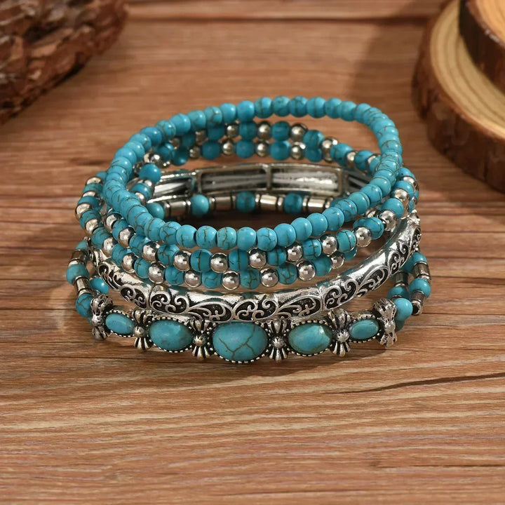 Set van 5 armbanden met turquoise kralen en zilverkleurige details.
