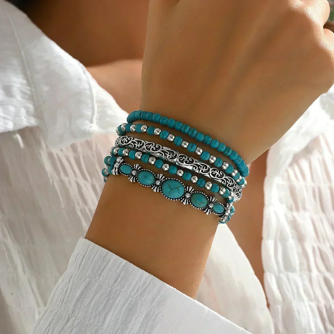 Set van 5 armbanden met turquoise kralen en zilverkleurige details.